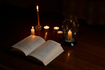 Reading a book by candlelight in a dark room. Blackout. Power outage, energy crisis. Problems with...