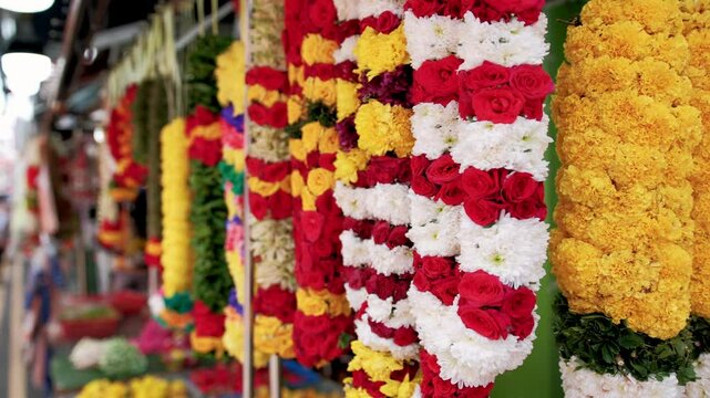 Colorful flower garlands hanging in bustling singapore market, representing cultural tradition with vivid festive decorations