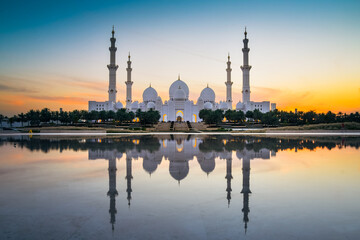 Sheikh Zayed Mosque in Abu Dhabi, UAE, at dusk with reflection in the water. Purple blue colorful tones at night architecture concept