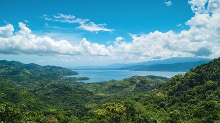 A breathtaking view of a lush green landscape with a calm blue lake and distant mountains under a clear blue sky with fluffy white clouds.