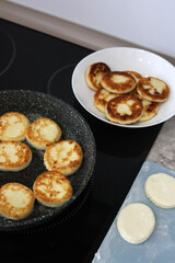 Process of making syrniki. Form round syrniki from curd dough. Baking cheesecakes on the stove.Vertical photo.