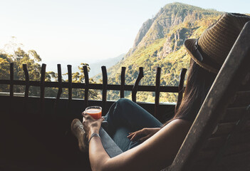 Woman sit in chair drink fresh mango juice in balcony viewpoint by breathtaking Ella Rock landmark...