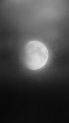 Mysterious moon behind misty clouds.