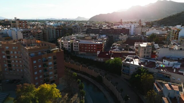 Drone point of view ancient spanish city of Orihuela, aerial shot of architecture and Segura River canal during sunny summer day. Costa Blanca, Alicante province. Spain