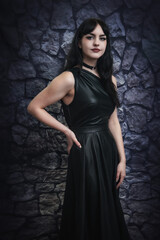 beautiful goth girl in black dress alternative punk rock gothic female model with black hair in front of stone background