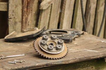 A mechanical gear and other metal parts placed on a wooden surface, possibly part of an old machine or tool, highlighting industrial textures	
