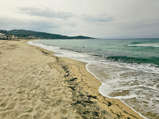 Peaceful beach retreat with gentle waves and soft sandy shore during overcast weather in Sarti on Sithonia peninsula, Greece