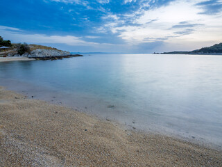 Tranquil beach with soft sand and calm water during twilight in a serene coastal landscape in Toroni on Sithonia peninsula, Greece