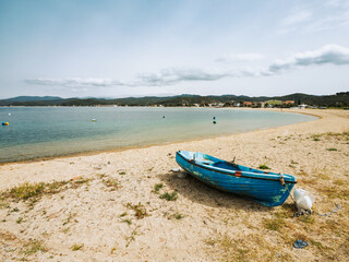 Calm seaside view with a blue boat on the sandy shore of a tranquil beach during the daytime in Toroni on Sithonia peninsula, Greece