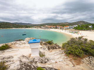 Scenic coastal view of a tranquil beach with boats and distant hills on a cloudy day at village Kalamitsi on Sithonia peninsula, Greece