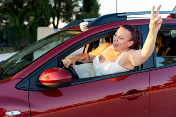 Bride making victory sign driving car after roadside breakdown
