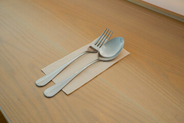 Knife and fork table setting,spoon silverware and white plate on wooden table in modern restaurant.