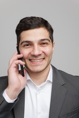 Smiling man in a suit talks on the phone, expressing joy and confidence in a modern setting