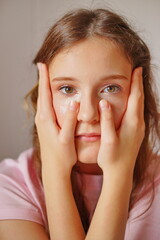 Cute girl playfully posing with her hands on her face, showcasing her adorable features and...