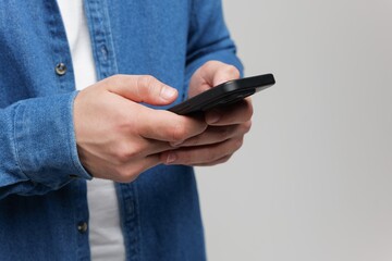 Engaging with technology while wearing a casual denim shirt in a minimalistic environment