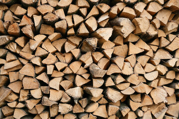 Neatly stacked firewood creates a textured background of natural wood.