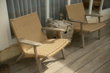 Woven rattan lounge chairs beside a rustic wooden stump table on a wooden deck