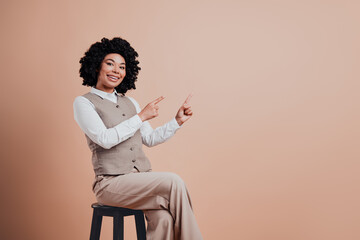 Confident young businesswoman with afro hairstyle gesturing and smiling in formal beige attire...