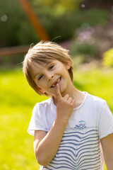 Close up portrait of preschooler child, boy, who lost his milk teeth, smiling with open mouth in garden