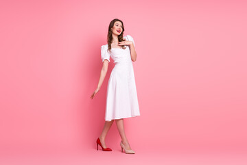 Elegant young woman in a white dress posing stylishly against a vibrant pink background, showcasing...