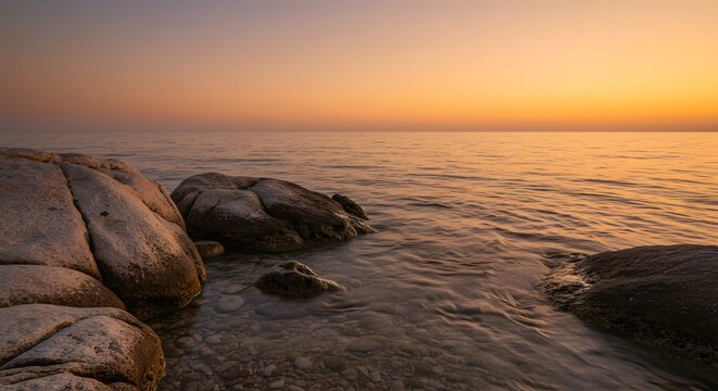 Minimalist rocky coastline with smooth waves at sunset