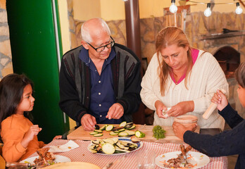 Happy latin family cooking together healthy dinner at house patio - Grandparents and grandchildren...