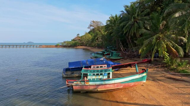 Overhead image of beach shacks and wooden boats by shore, Thailand. Aerial drone video