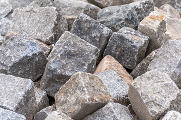 Close-up of paving stones. Irregularly shaped, coarse granite paving stones lie close together. The surface details show structure, color, and aging