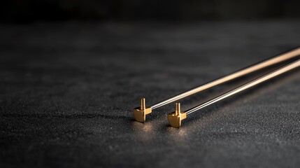 A pair of gold chopsticks on a black surface.