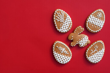 Romantic decorated Easter gingerbread cookies in a shape of egg and bunny, red background, copy space for text