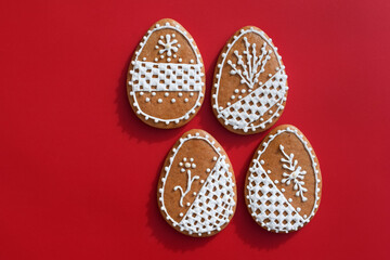 Romantic decorated Easter gingerbread cookies in a shape of egg, red background, copy space for text