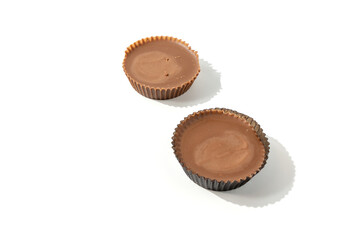 Two peanut butter cups next to each other on a white background. An ideal snack combination of chocolate and peanut butter.