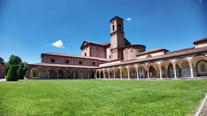 Ferrara, Italy - May 17, 2025: Wide angle view capturing the Charterhouse of Ferrara, featuring a church, bell tower, and cloister amidst lush green lawns under a clear blue sky