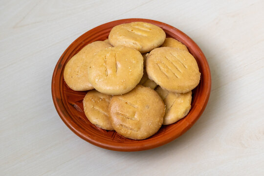 Tasty crispy Bakarkhani on clay plate on light wooden backdrop. Baqarkhani, a thick spiced flatbread, is part of Mughlai cuisine.