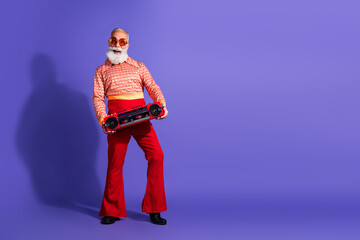 Elderly man in retro outfit holding a boombox, styled with red flared pants and purple background,...