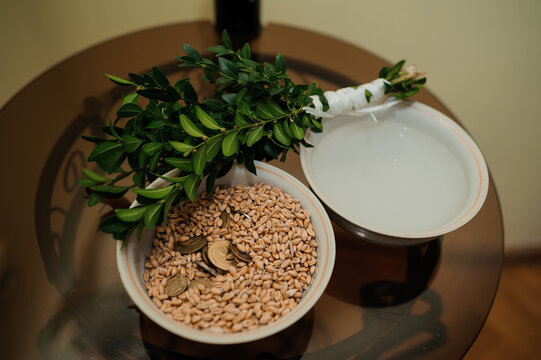 Greek wedding ritual preparation with olive branch crown, coins in pot, and traditional items for blessings and prosperity ceremony.
