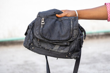 A woman displays a bag against a blurred background. Her fashionable black fabric handbag, used for...
