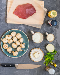 Ingredients for beef stroganoff with mushrooms and dairy on gray surface