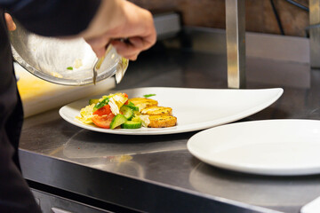 Chef preparing gourmet dish with sautéed vegetables and grilled tofu
