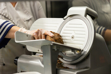 Chef slicing meat with deli slicer in professional kitchen