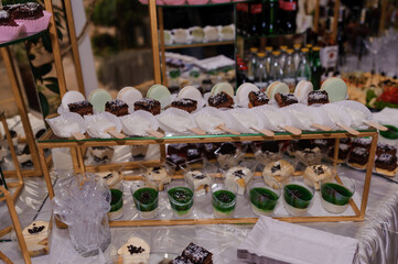 Elegant Dessert Display at Event with Macarons, Chocolate Treats and Green Parfaits on Golden...