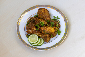 Spicy Iranian chicken karahi, kadai, or bhuna curry on a white plate with a wooden background. Delicious hot dish.