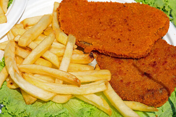 breaded fried canre cutlets and yellow fried potatoes on a bed of green lettuce
