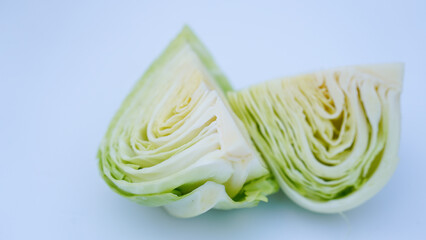 A cabbage cut in half, showcasing its fresh green leaves and internal layers, isolated on a plain...
