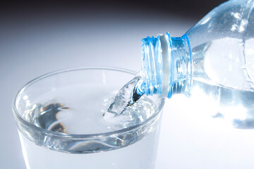 Water Pouring from Bottle into Clear Glass with Soft Background
