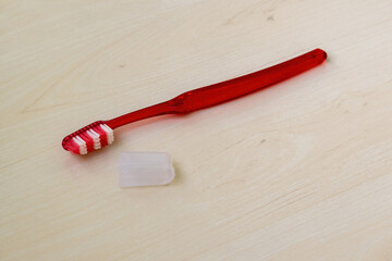 Red zigzag adult toothbrush with cap on wood. Dental care, soft bristles, ergonomic design.
