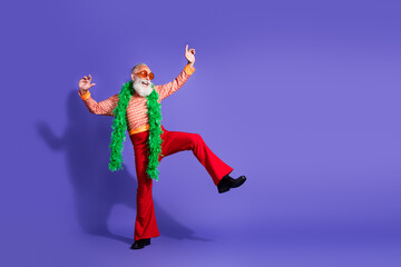 Stylish senior man in retro clothing dancing energetically on a vibrant purple backdrop, showcasing vintage charm