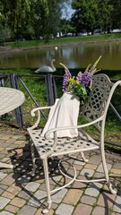 Peaceful summer park view with a white swan resting near a small pond, surrounded by lush greenery.