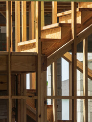 Stairway with risers of particle board and treads of wood, a wooden landing, and change of direction inside a bi-level townhouse under construction in a residential development in southwest Florida