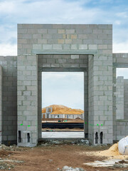 Street view of the front entrance of a house under construction, with framed view of a new house with prefabricated roof trusses in place, in a suburban residential development in southwest Florida